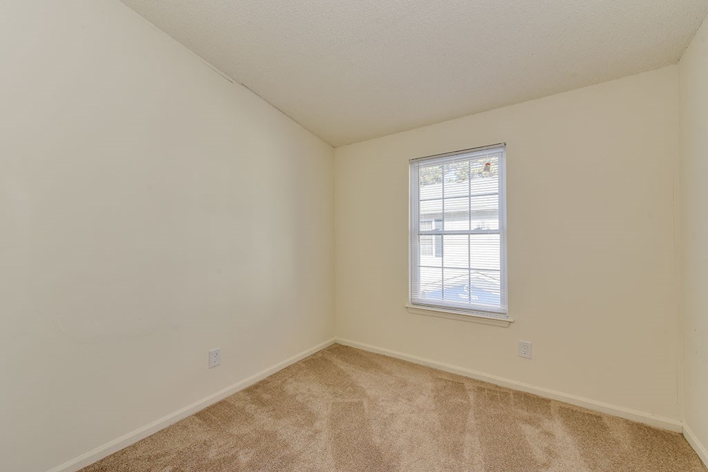 a bedroom with a window and a carpeted floor