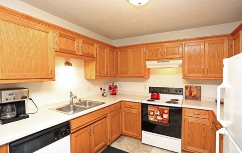 a kitchen with wooden cabinets and black appliances and white counter tops