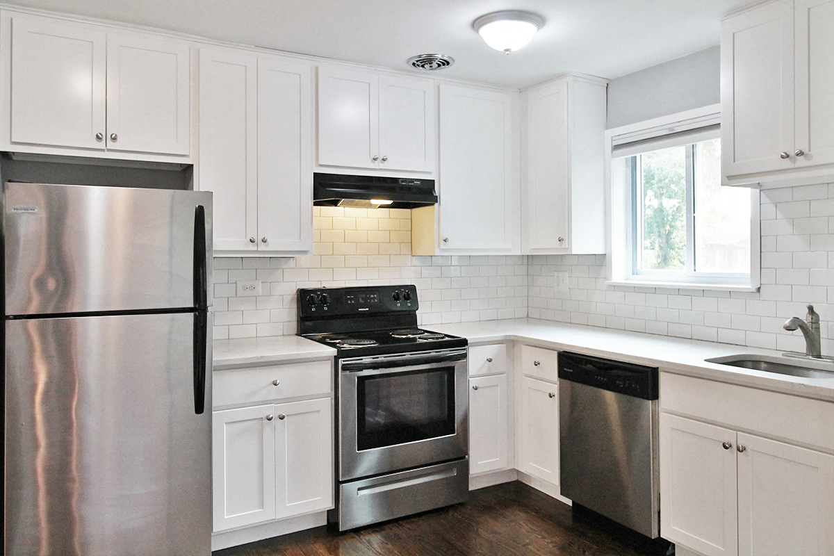 a white kitchen with stainless steel appliances and white cabinets