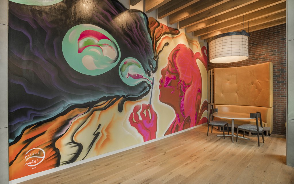 a mural of two women on a wall in a room with a chair