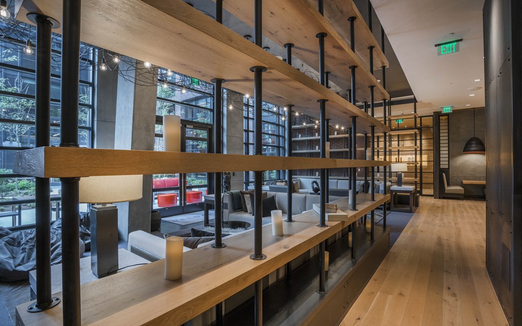 the lobby of a hotel with long wooden benches and a large glass walled room