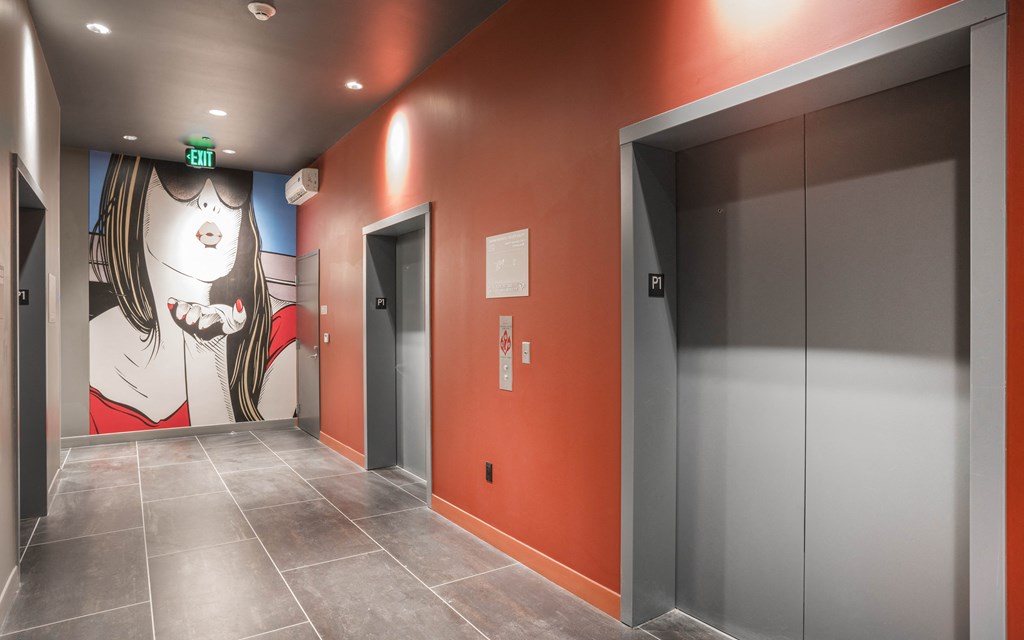 a hallway with two elevators and a mural on the wall