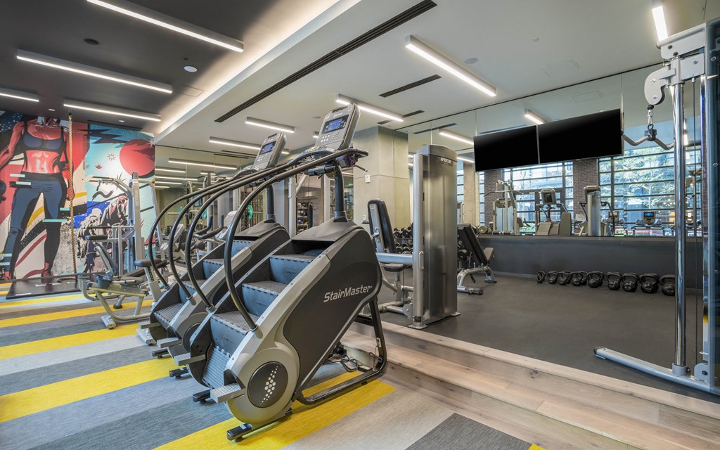 a gym with cardio equipment and weights on the floor of a building