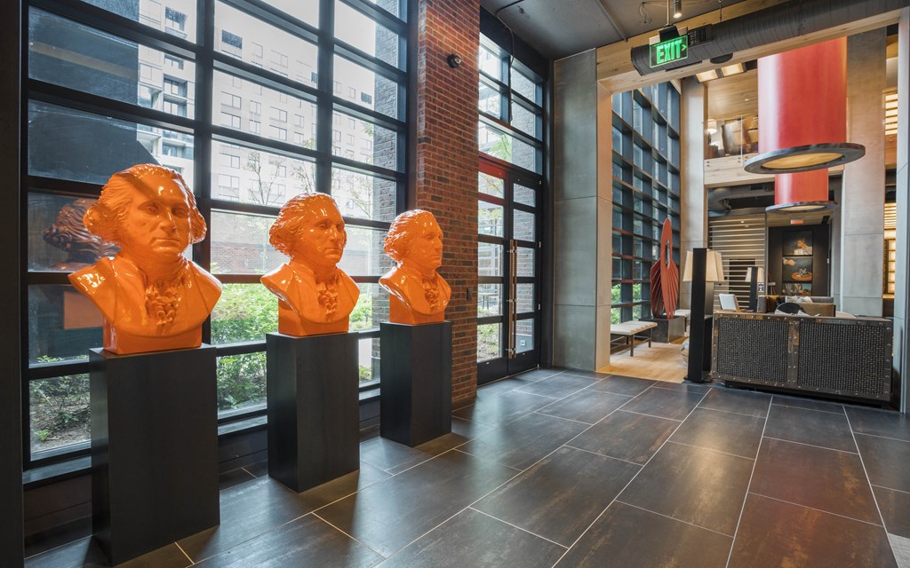 three busts in the lobby of a building with large windows