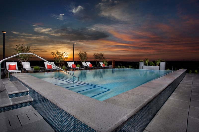 a swimming pool with chairs around it at sunset