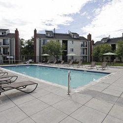 a swimming pool with chaise lounge chairs in front of a building