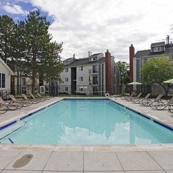 a swimming pool with chairs around it in front of a building