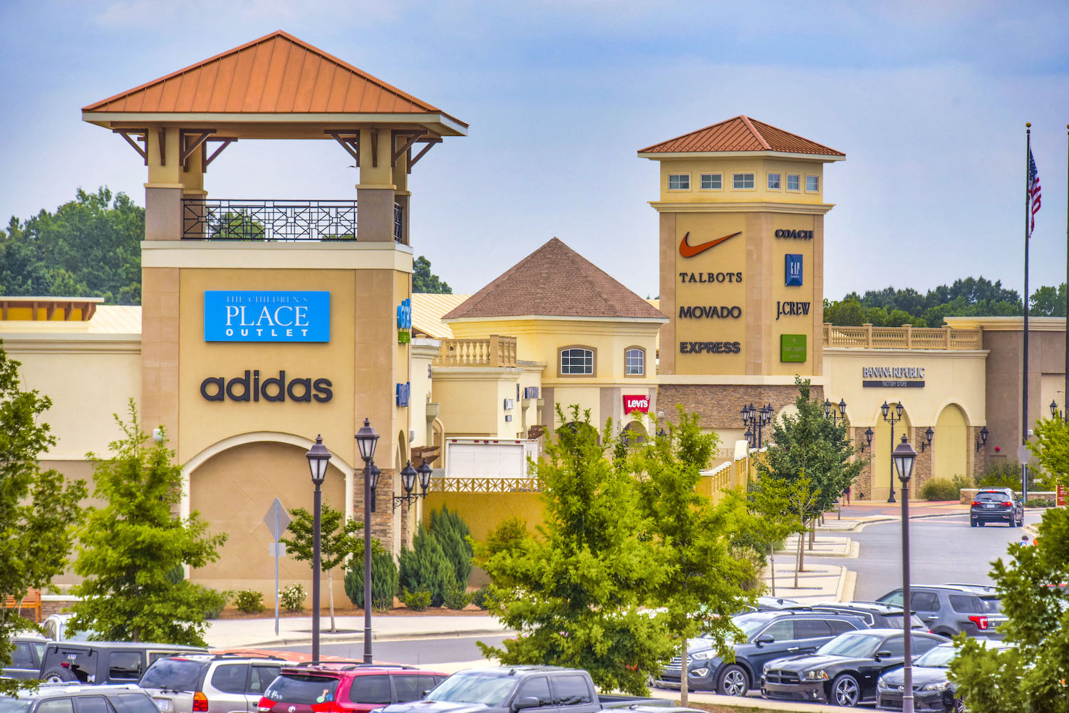 a parking lot with cars in front of an adidas shopping center