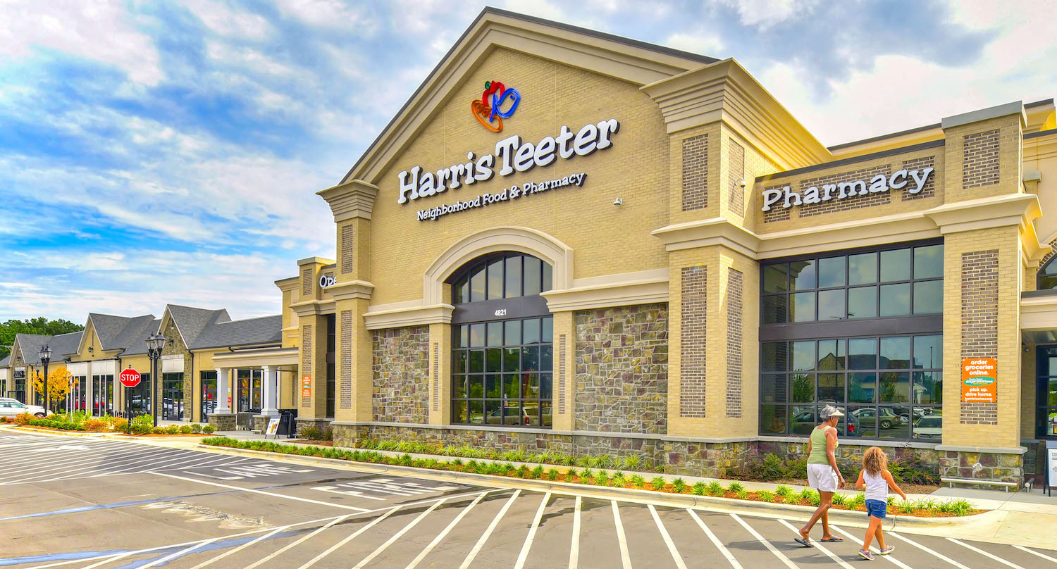 a man and woman walking in front of a shopping mall with a hanes legacy