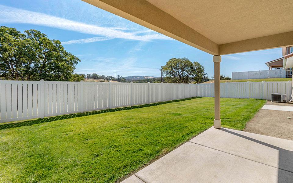 a backyard with a white fence and grass and a sidewalk