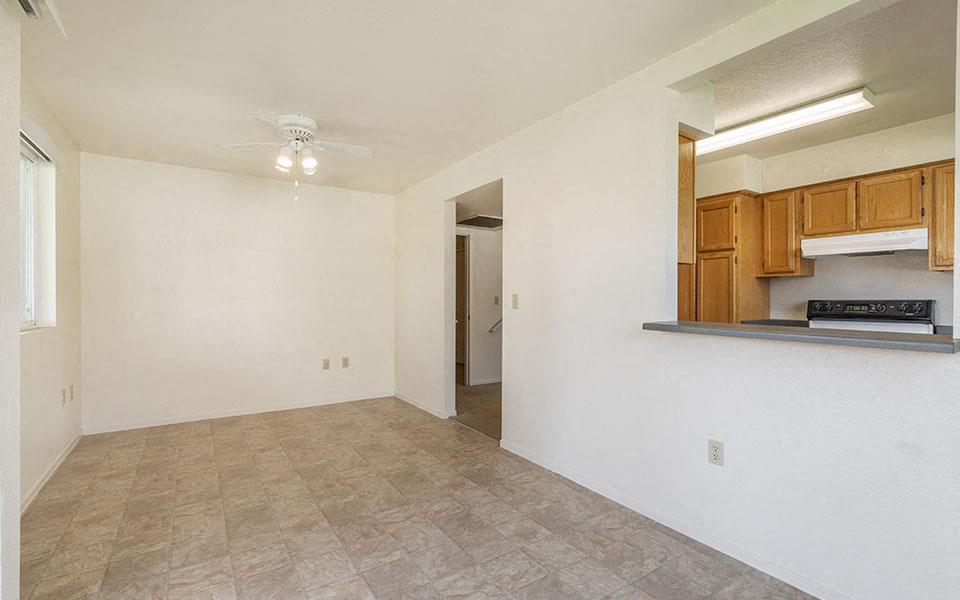 an empty living room and kitchen with a ceiling fan