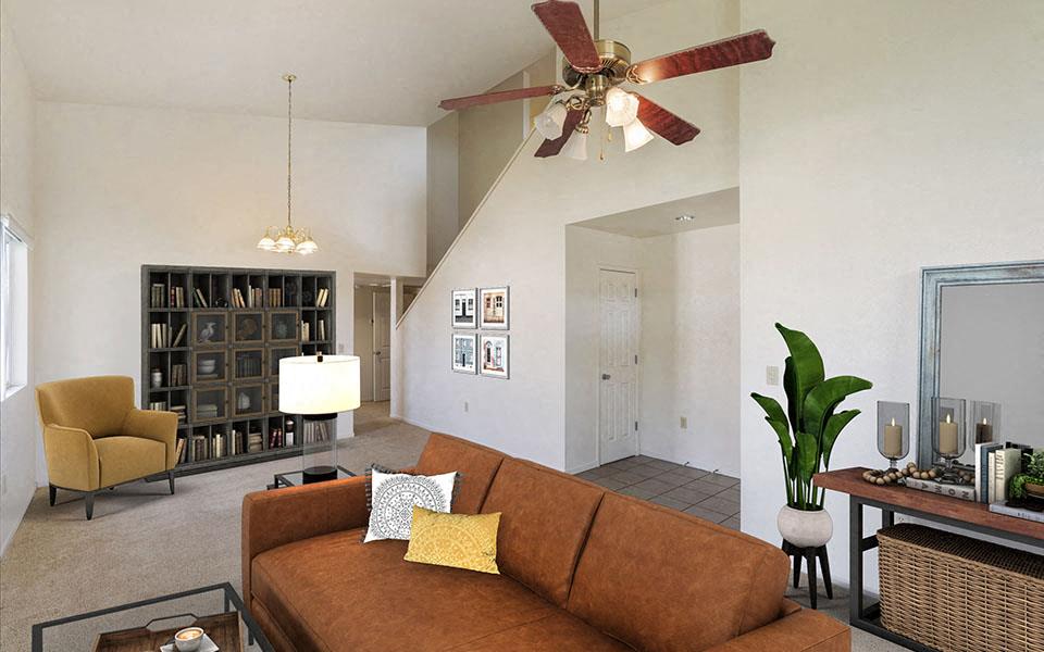 a living room with a brown couch and a ceiling fan