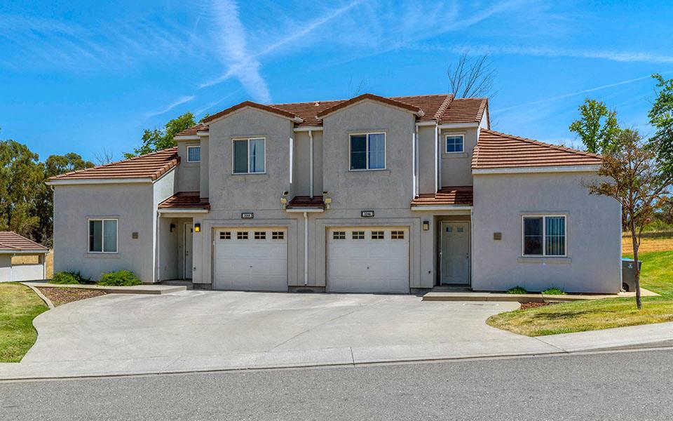 a beige house with a driveway and garage doors