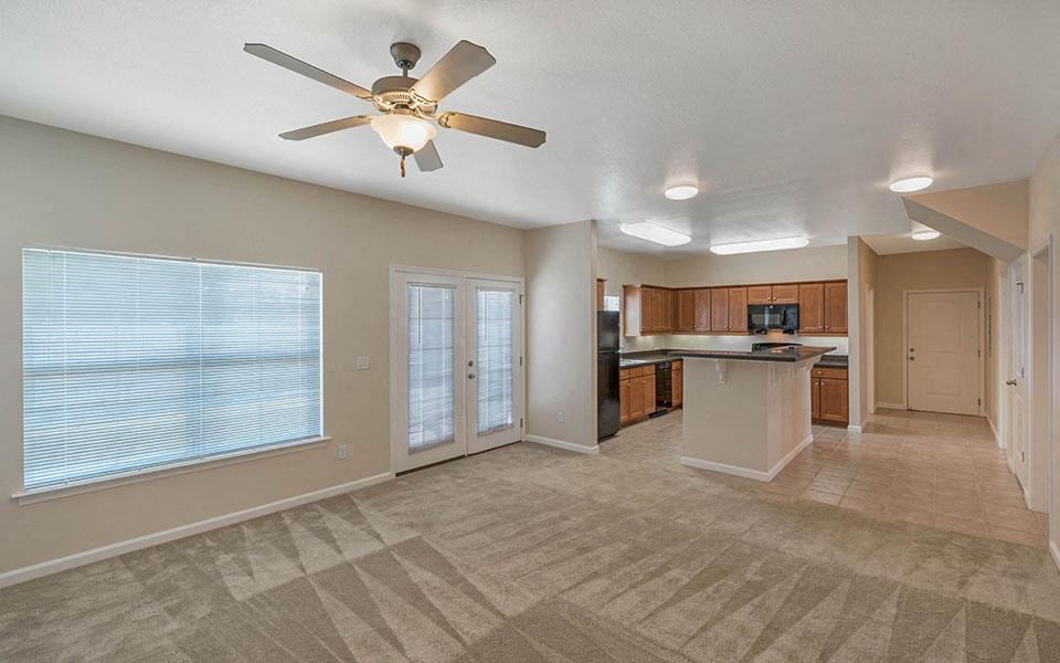 an empty living room and kitchen with a ceiling fan