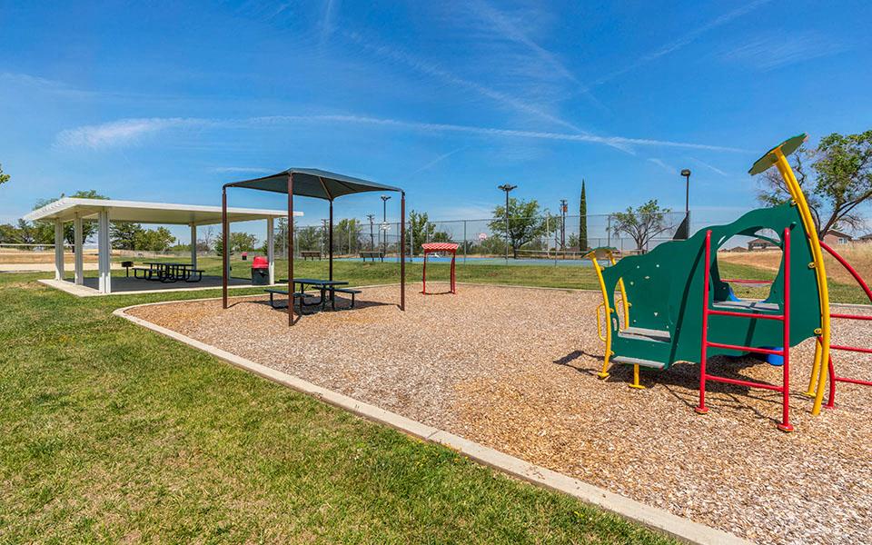 a playground with a swing set and a picnic table