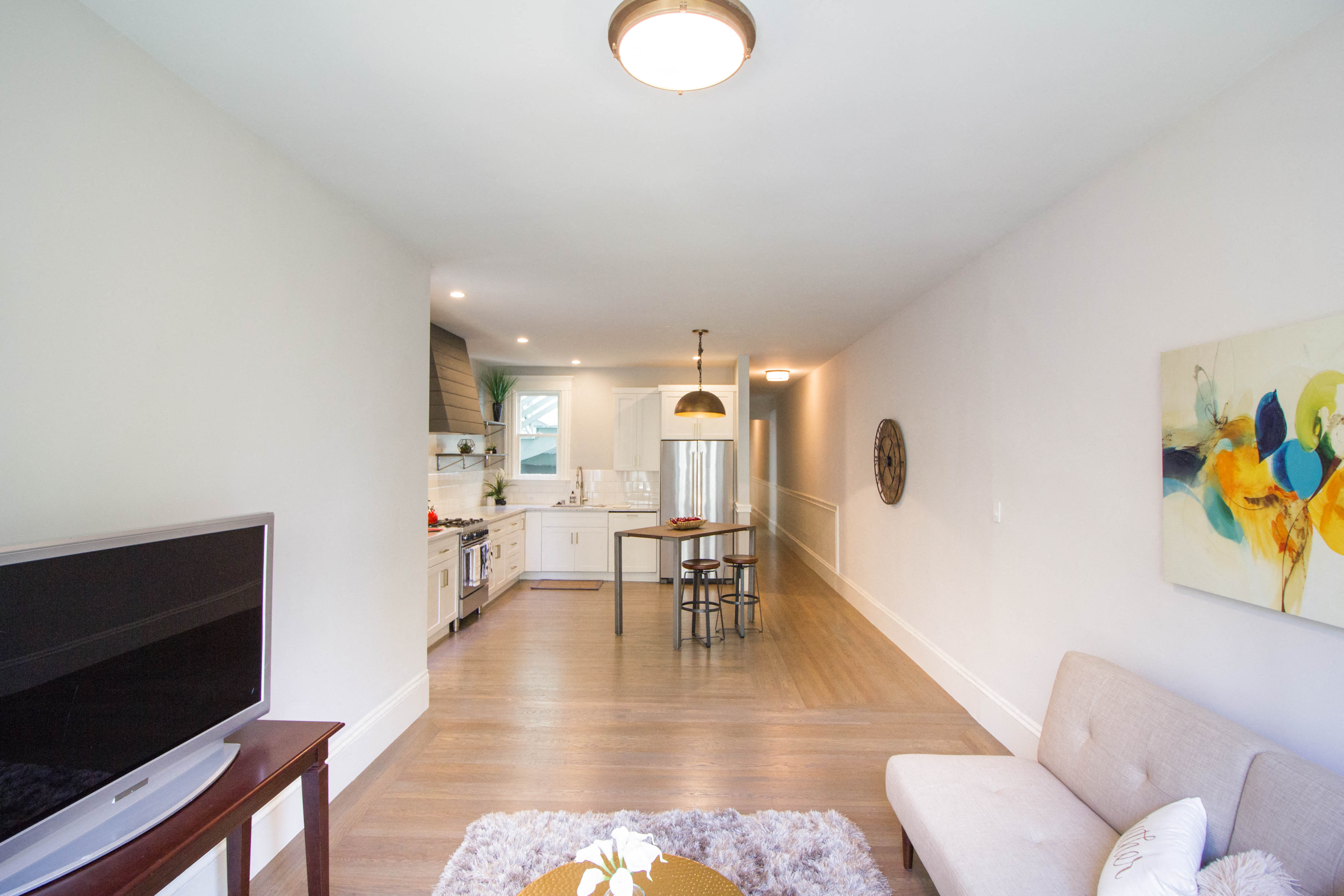 a living room with a couch and a tv and a kitchen