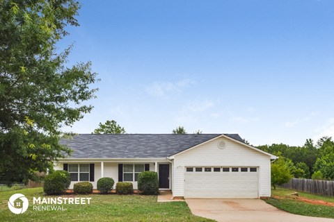a small white house with a blue roof on a lawn