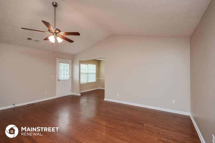 the spacious living room with ceiling fan and wood flooring