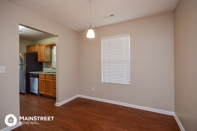 the living room and kitchen of an apartment with wood flooring and a window
