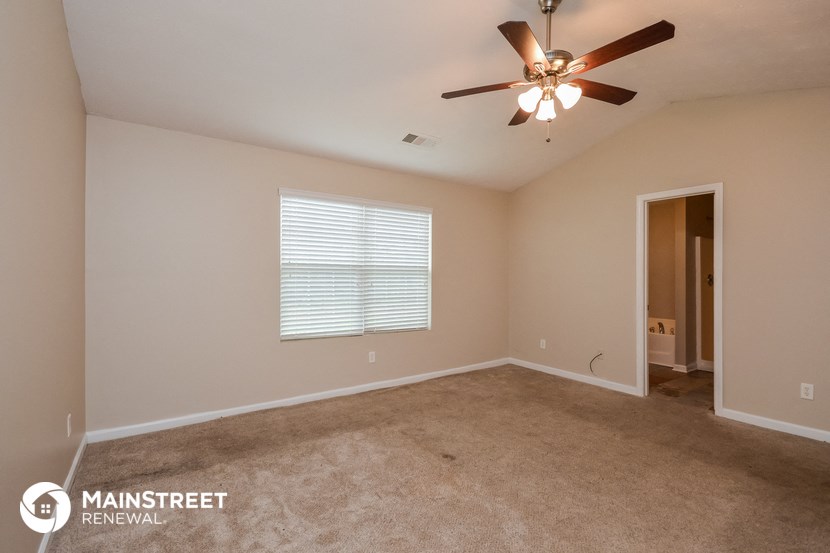 the spacious living room with beige carpet and a ceiling fan