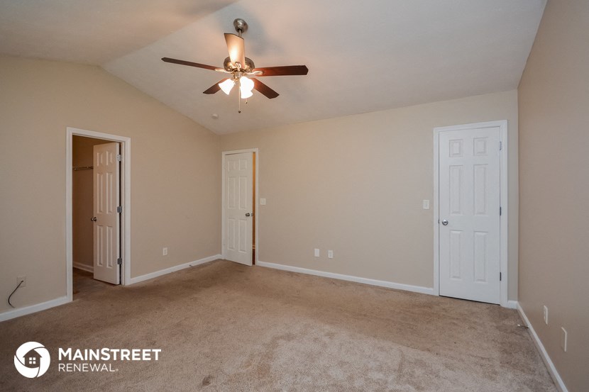 the spacious living room with carpet and ceiling fan