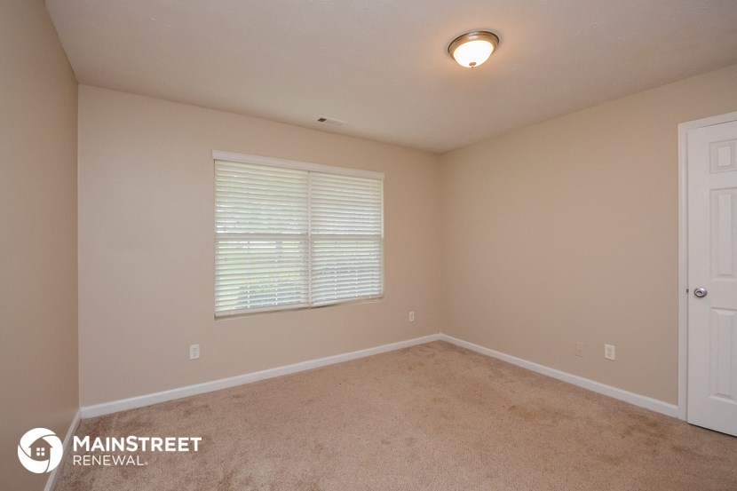 the upstairs bedroom has a carpeted floor and a large window