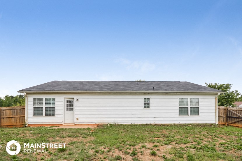 a small white house with a yard and a wooden fence