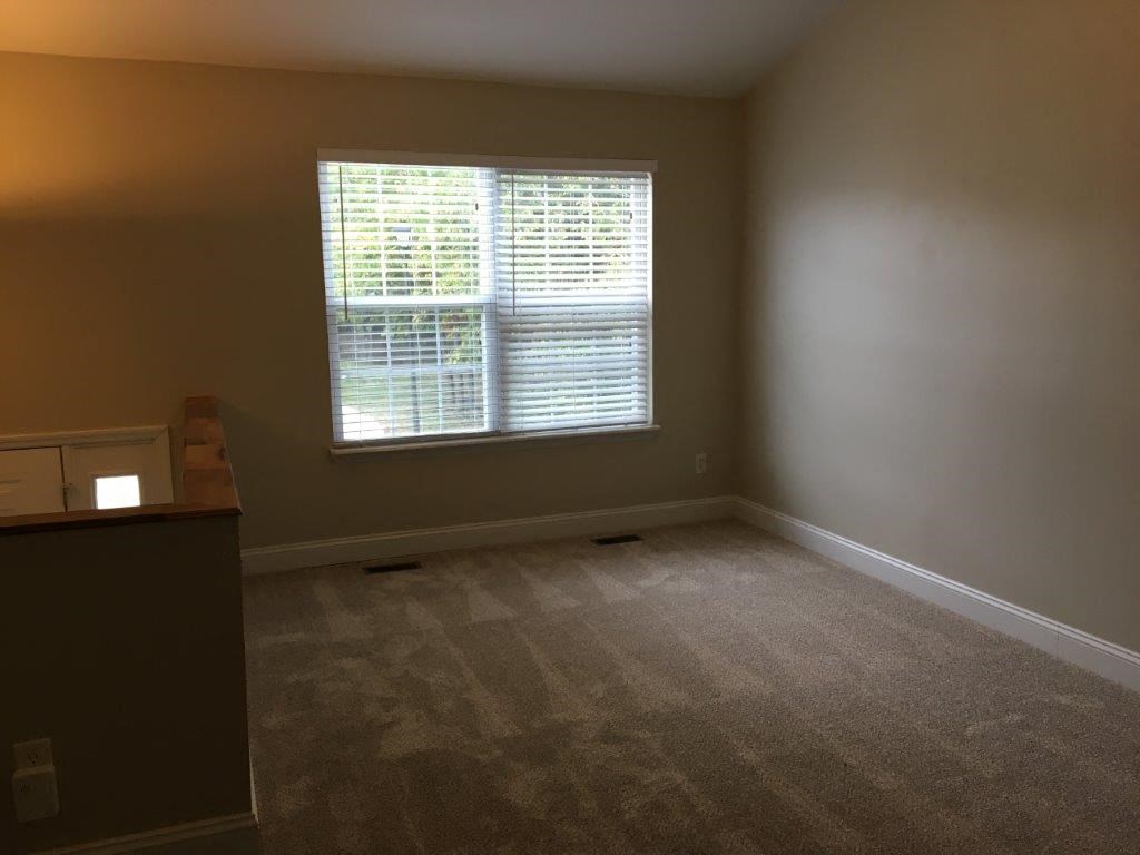 an empty living room with a window and carpet