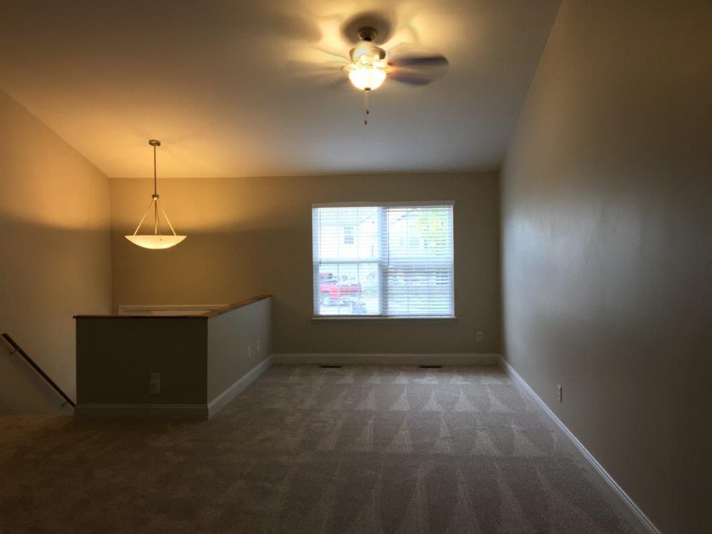 an empty living room with a ceiling fan and a window
