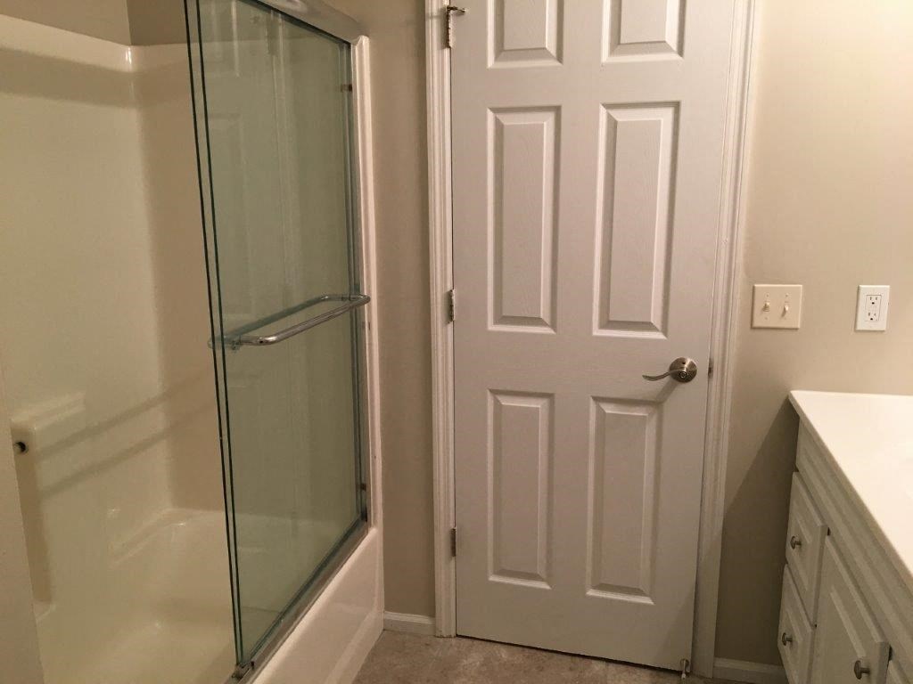 a bathroom with a shower and a white door