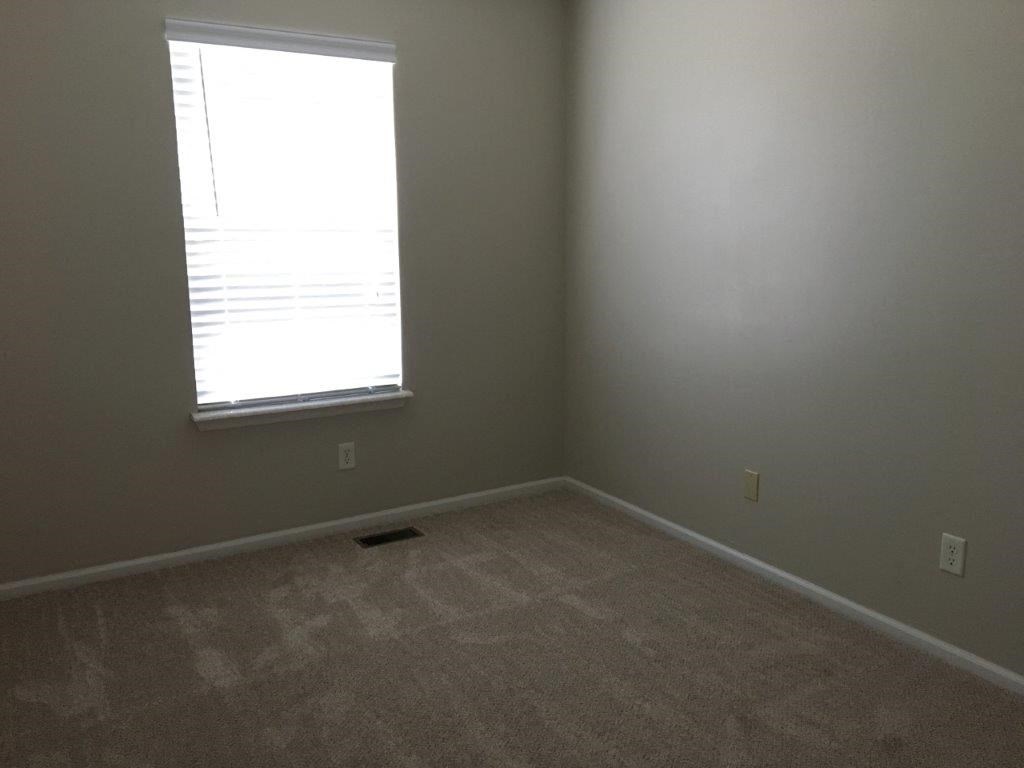 an empty room with a window and a carpet