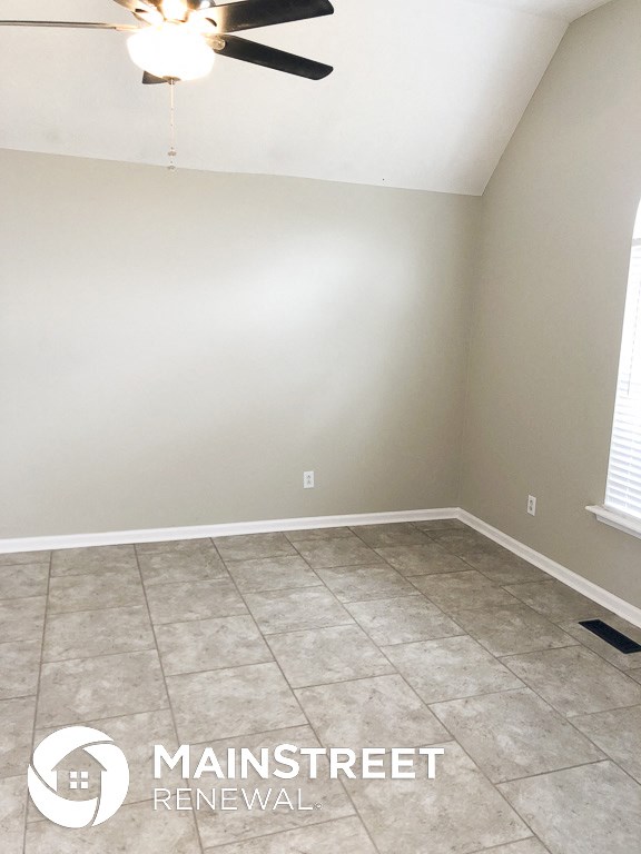 an empty room with a ceiling fan and a tiled floor
