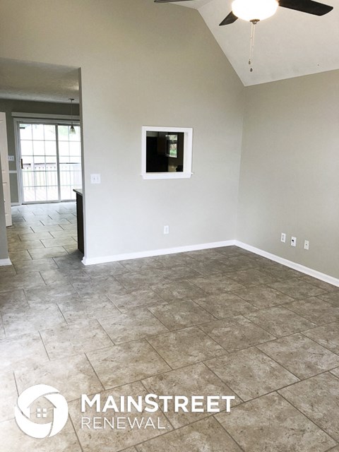 an empty living room with tile flooring and a ceiling fan