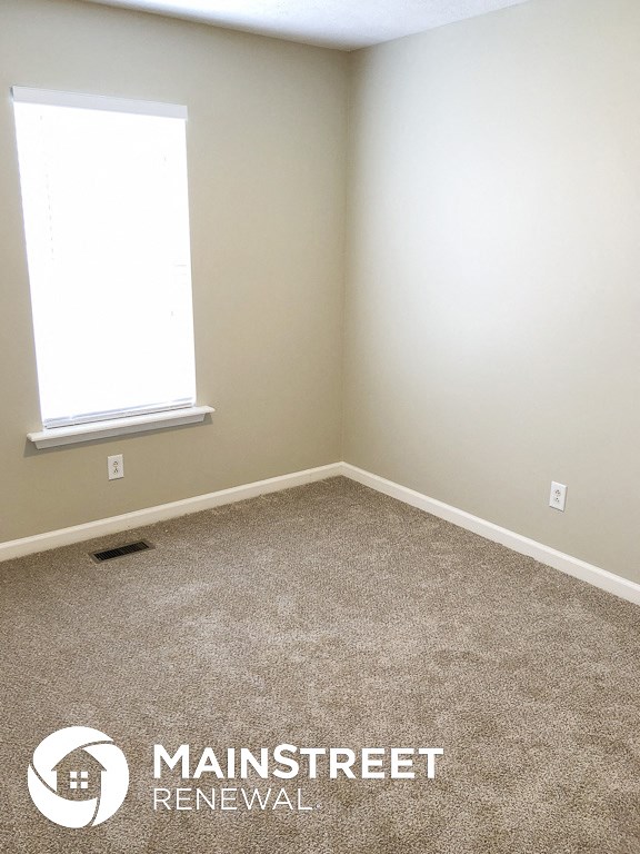 an empty room with a carpeted floor and two windows