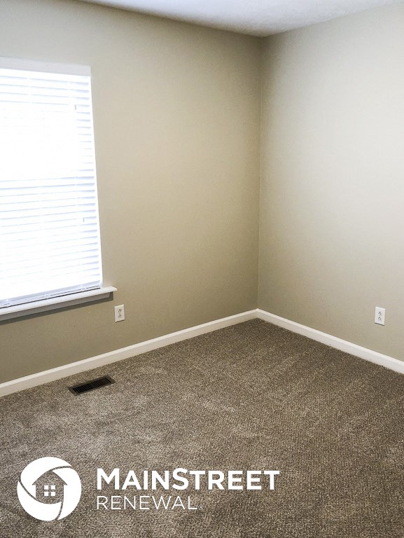 a small room with a carpeted floor and a window