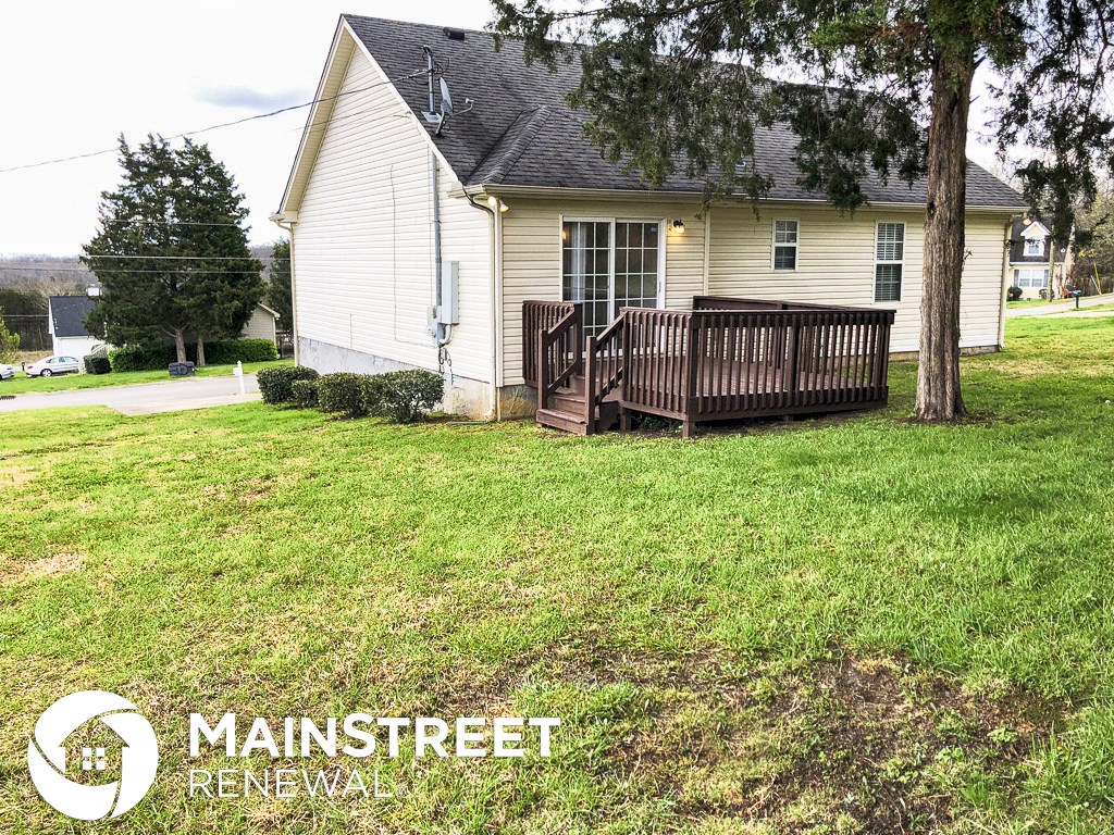 a house with a wooden deck in front of a tree