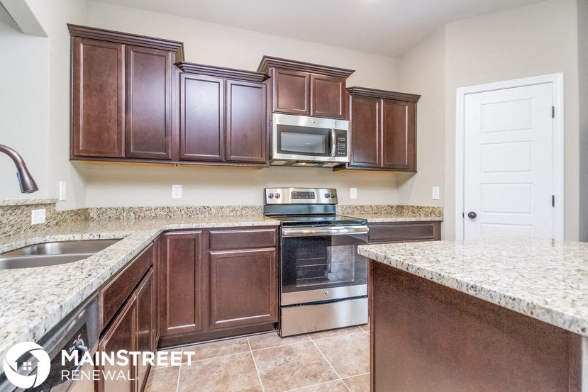 a kitchen with wooden cabinets and granite counter tops and a stove and microwave