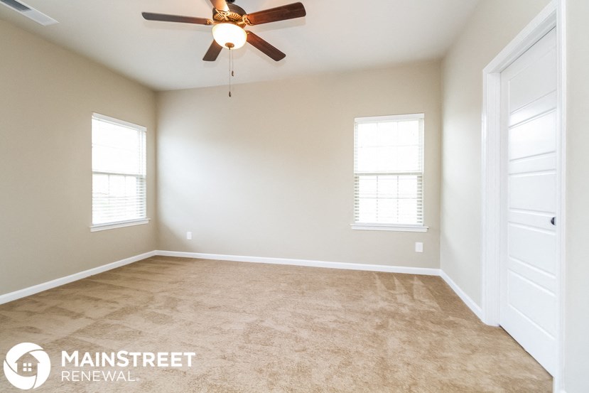 an empty room with a ceiling fan and two windows
