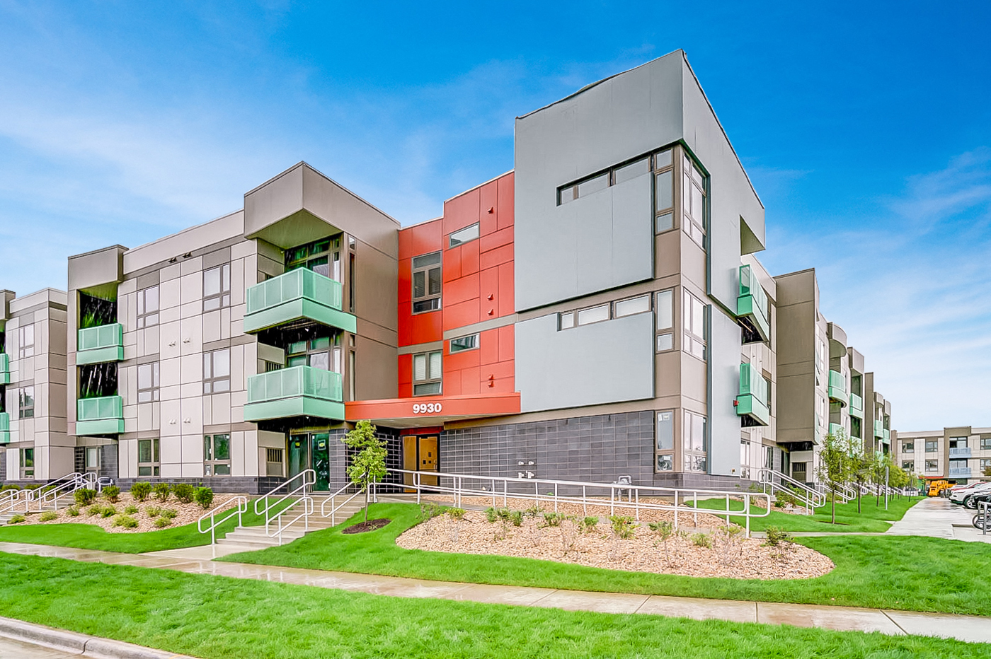 a modern apartment building with green grass and a sidewalk