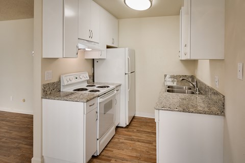 a kitchen with white appliances and granite counter tops and a white refrigerator
