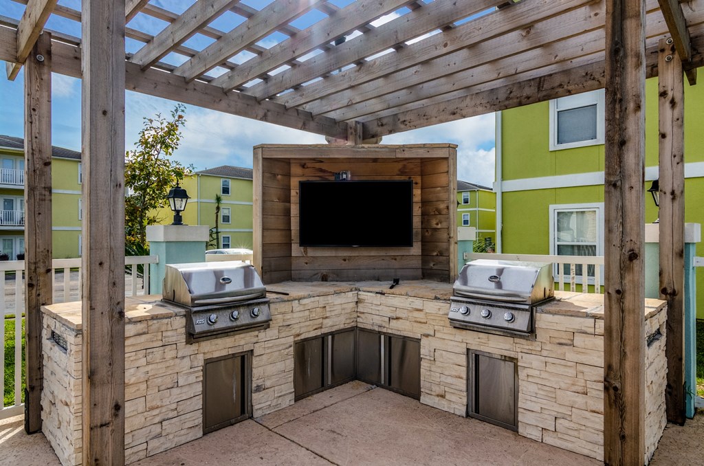 a outdoor kitchen with a tv and a wooden structure
