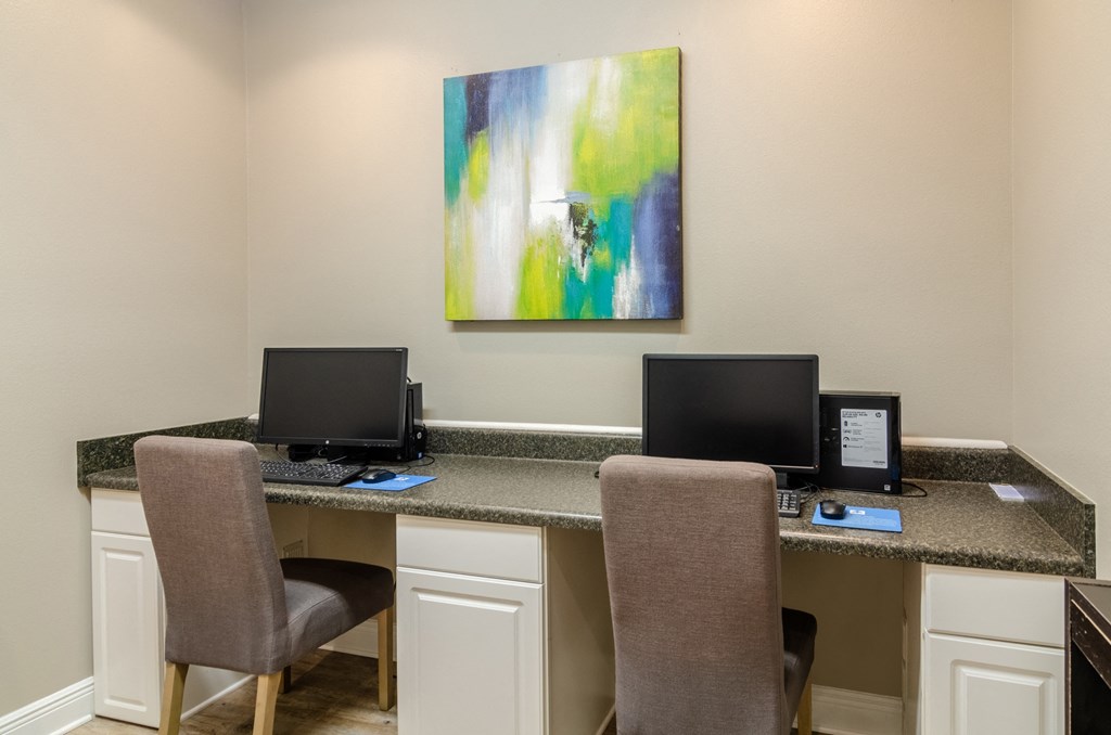 two computers sitting on a counter with two chairs