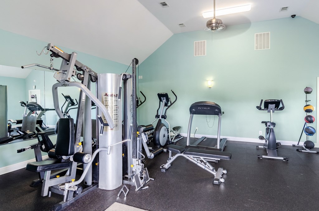 a gym with cardio equipment and weights on the floor