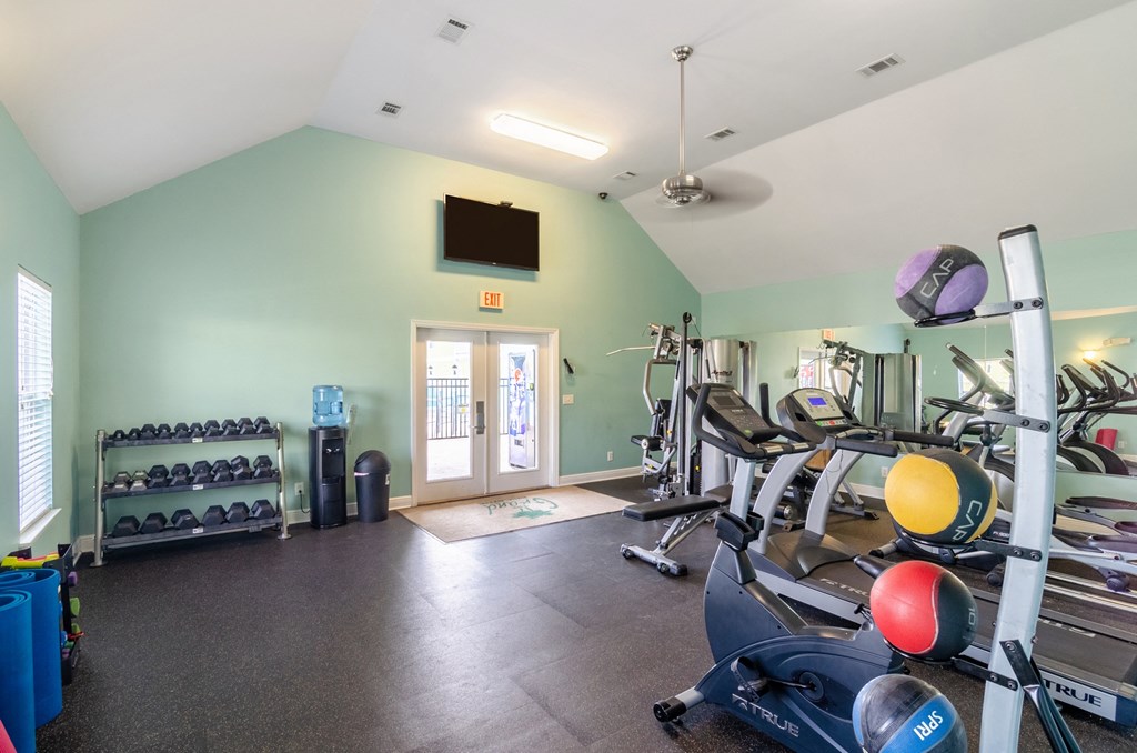 a gym with various exercise equipment and a tv on the wall