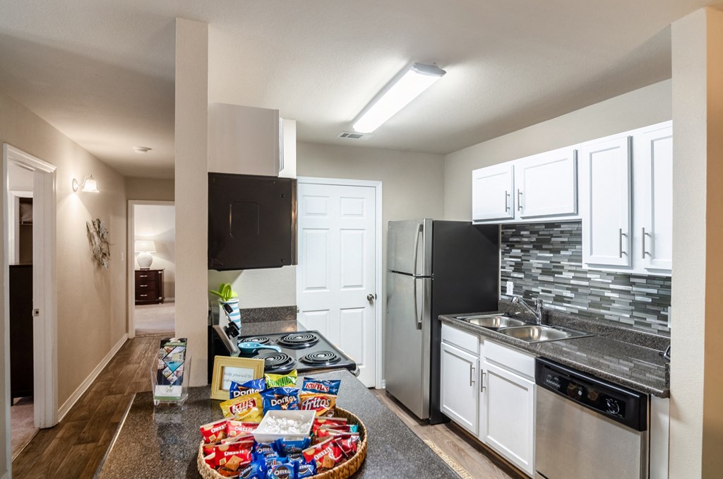 a kitchen with white cabinets and stainless steel appliances and a table with snacks