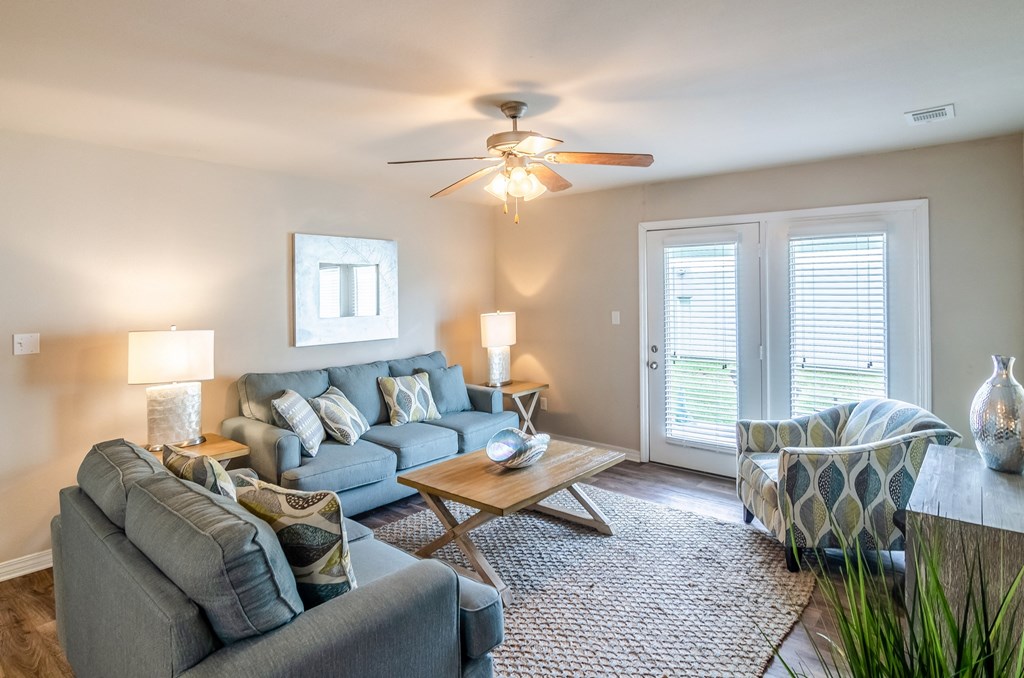 a living room with a couch and a chair and a ceiling fan
