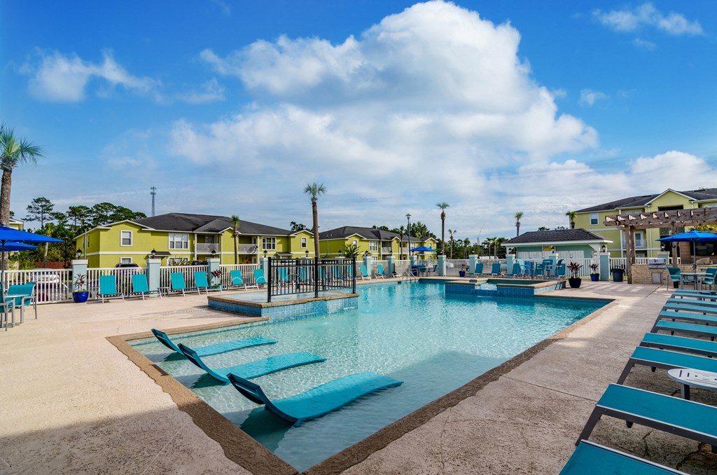 our resort style swimming pool is surrounded by blue chairs and yellow buildings