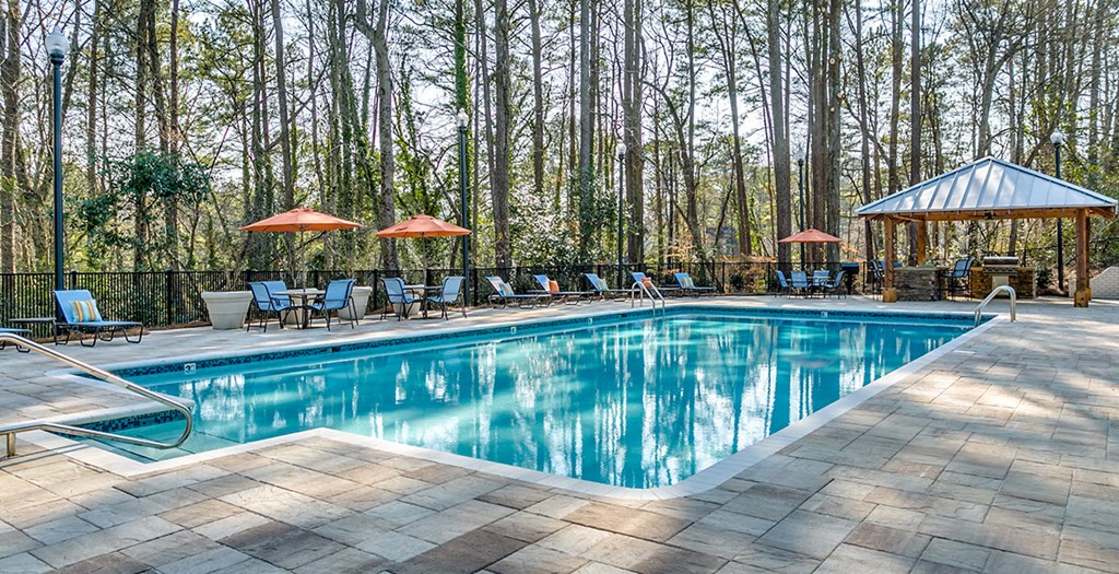 the swimming pool is surrounded by chairs and umbrellas