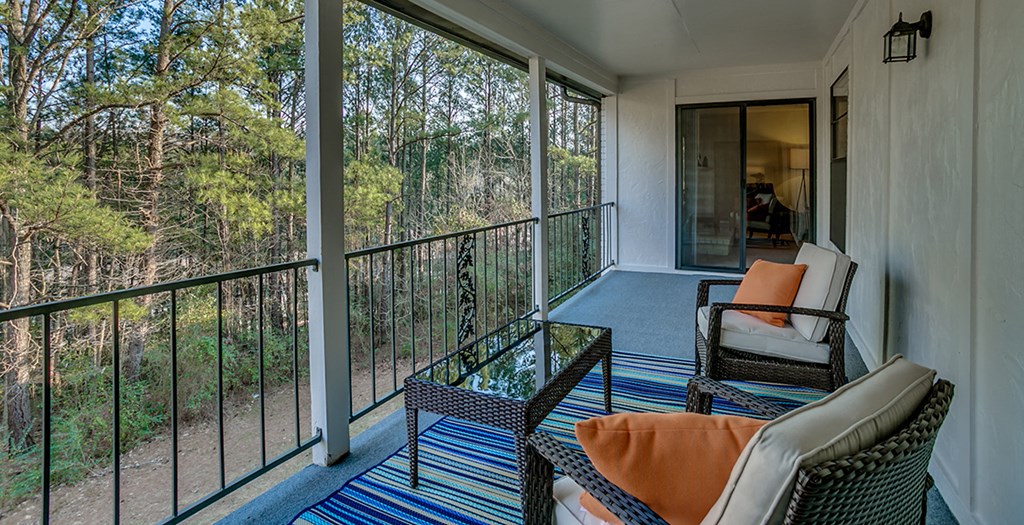 a balcony with two chairs and a glass table