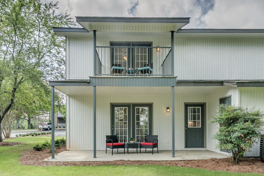 the front porch of a white house with a table and chairs on it